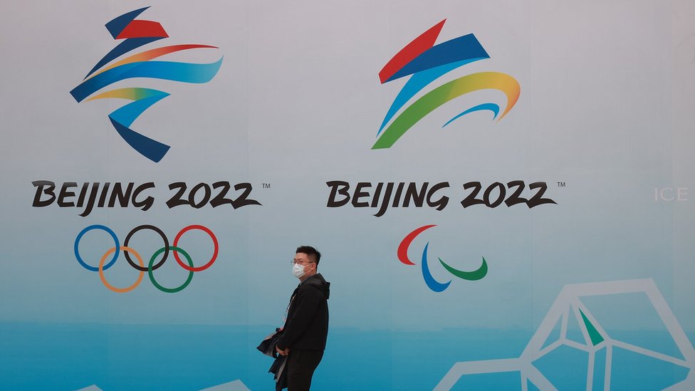 北京水立方一位途人走過2022年北京冬奧會與冬殘奧會標誌（9/4/2021）