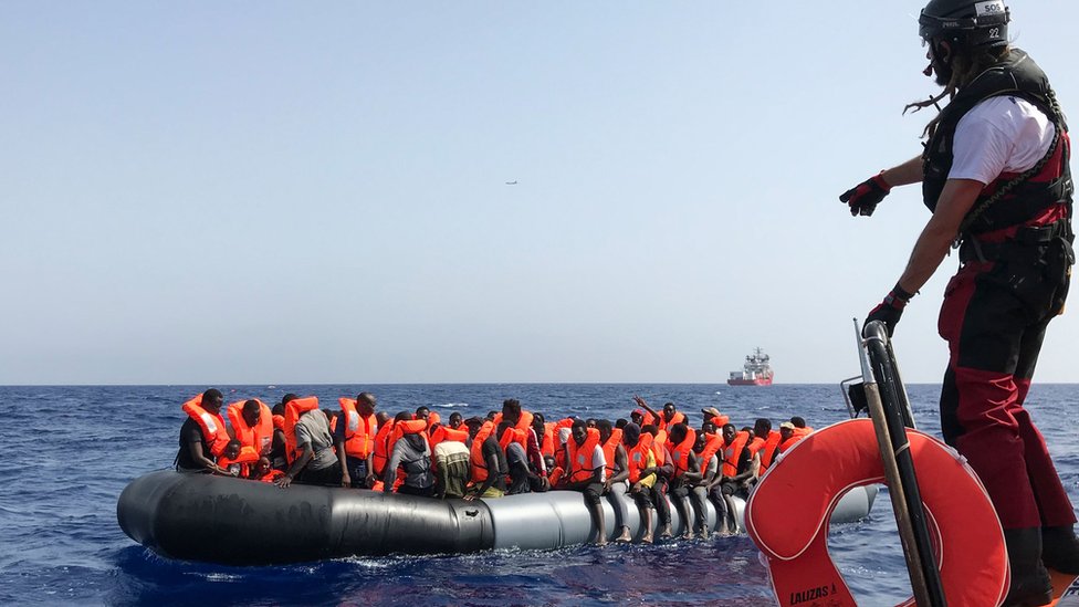 9 августа член экипажа спасательного корабля «Океан Викинг» помогает мигрантам на лодке