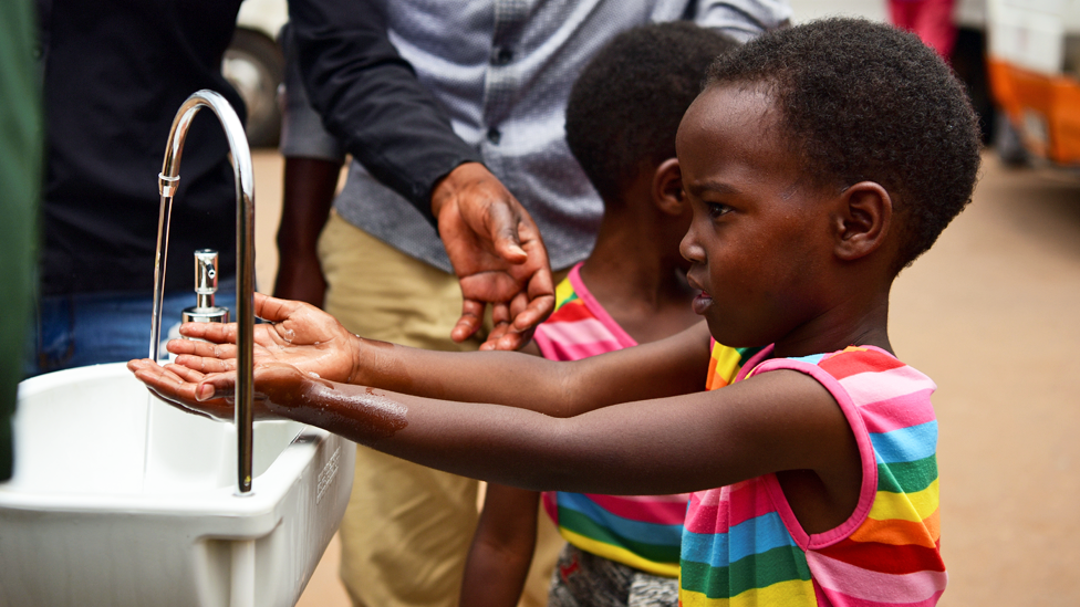 فتاة تغسل يديها يوم الأربعاء في أحد الأحواض التي أقيمت في محطات الحافلات في عاصمة رواندا ، كيغالي ، كجزء من تدابير الاحترازية لوقف انتشار فيروس كوفيد 19 .