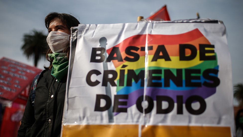 Mujer con una pancarta que dice Basta de crímenes de odio
