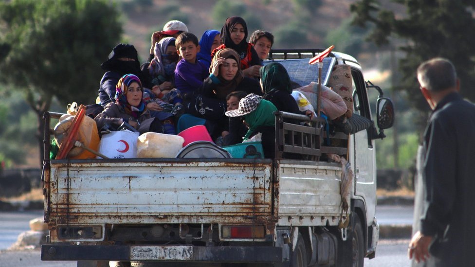 Перемещенные сирийцы сидят в кузове грузовика, когда они бегут по шоссе M4, в Арихе, провинция Идлиб (8 июня 2020 г.)