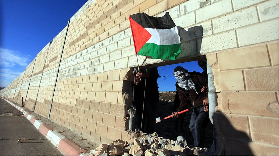 Palestinos en un boquete del muro