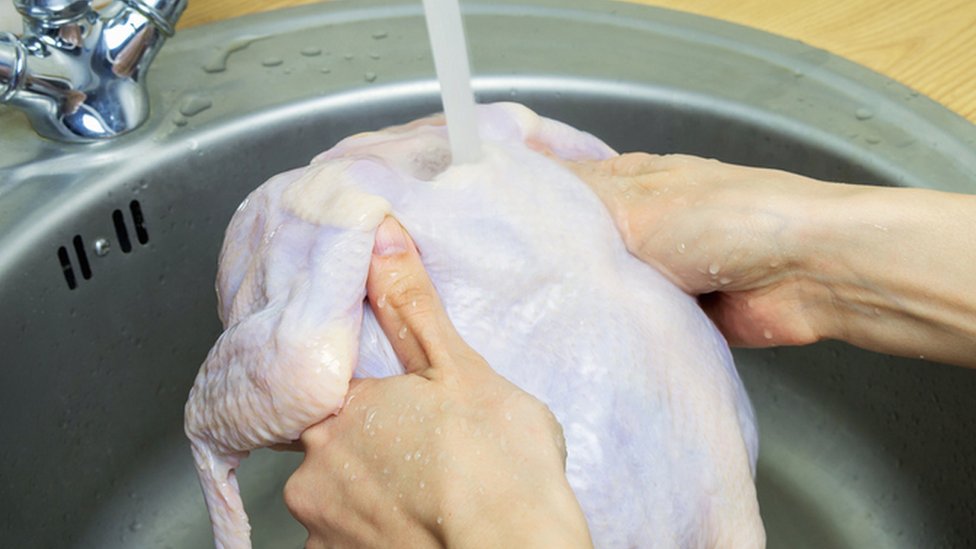 Persona lava un pollo en un fregadero
