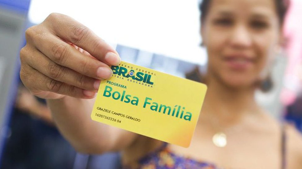 Mulher mostra cartão do programa Bolsa Família