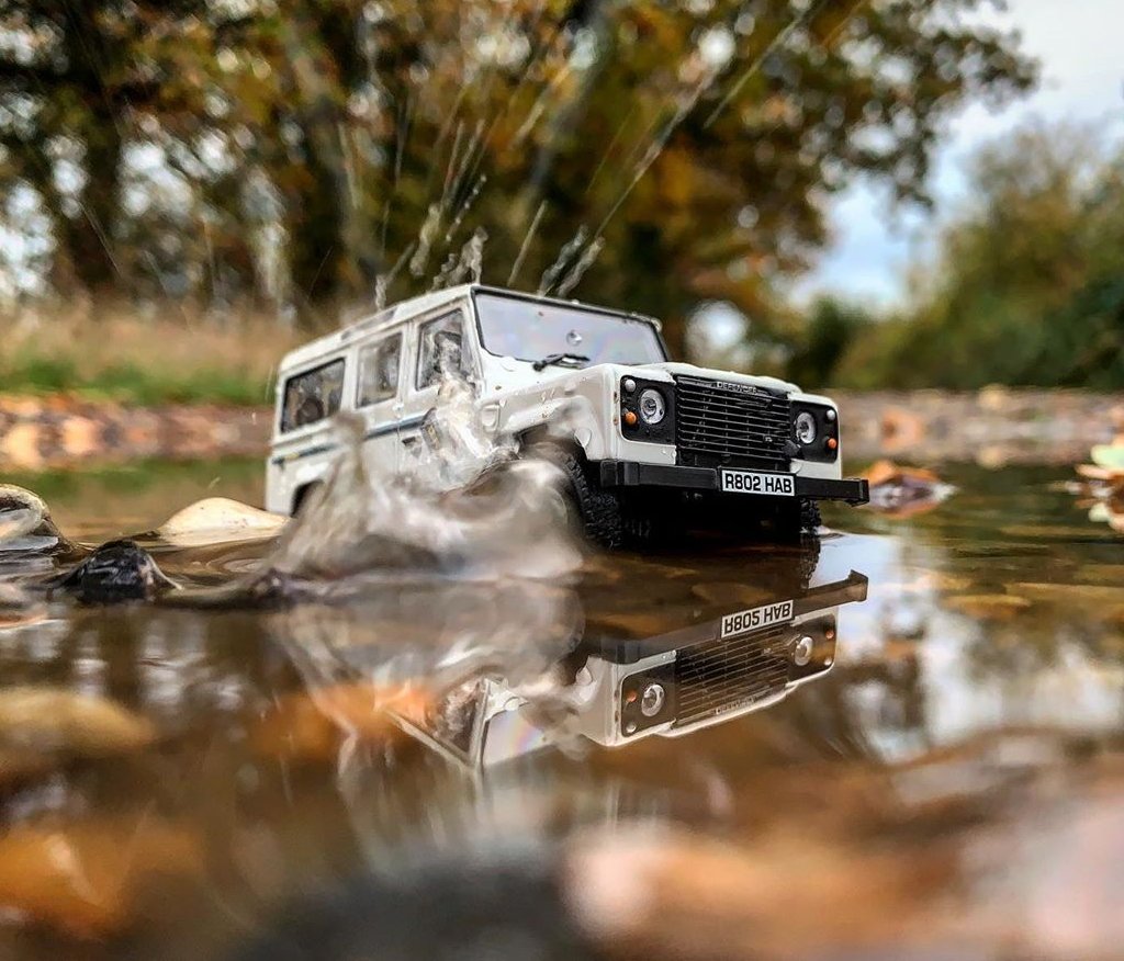 Белая модель Land Rover плещется в луже