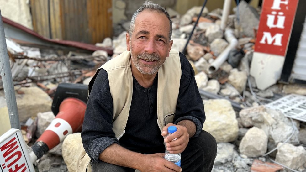 Ibrahim Sener, pictured sitting among the rubble outside a shop in Antakya
