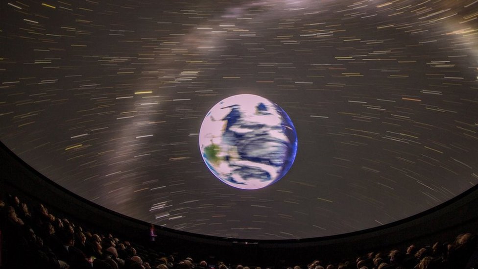Una imagen desde dentro de un planetario que muestra la tierra y las estrellas.