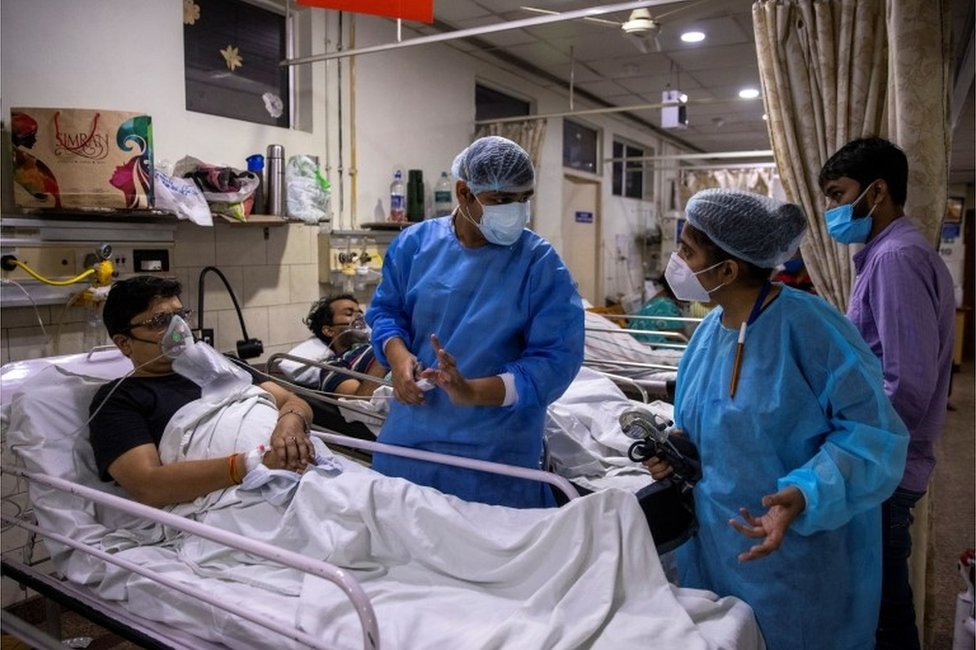روهان أغاروال، طبيب مقيم يعالج مرضى كوفيد، يتحدث إلى زميل أثناء رعايته لمريض خلال مناوبته التي استمرت لـ 27 ساعة مستشفى هولي فاميلي في نيودلهي بالهند. 1 مايو/أيار 2021 .