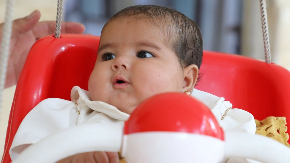 Afraa on a red baby swing