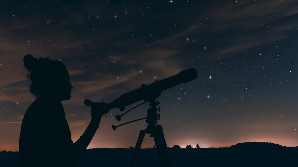 žena gleda kroz teleskop