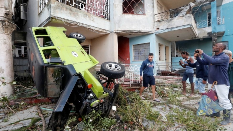 Personas fotografían un auto volcado afectado por el tornado. Personas fotografían un auto volcado afectado por el tornado.