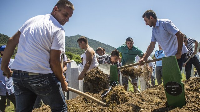 Family members and volunteers bury one of the 136 coffins of newly-identified victims of the 1995 Srebrenica massacre into its final grave mass funeral during the 20th anniversary of the massacre at the Potocari cemetery and memorial on July 11, 2015 in Srebrenica