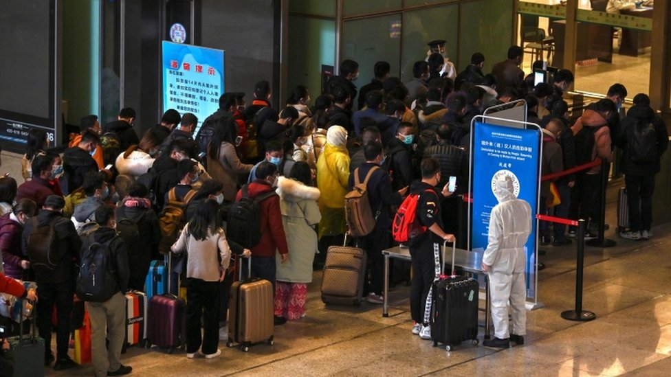 Пассажиры в масках стоят в очереди после прибытия на железнодорожный вокзал в Ухане, центральной провинции Китая Хубэй, 28 марта 2020 года