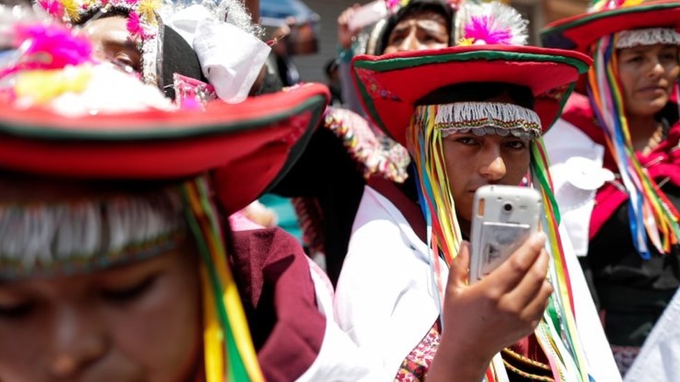 Коренной боливиец держит сотовый телефон и наблюдает, как бывший президент Боливии Эво Моралес возвращается в свою родную страну из изгнания в Аргентине, в приграничный город Виллазон, Боливия, 9 ноября 2020 года.