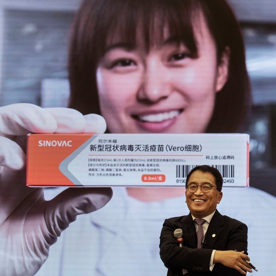 Yin Weidong, presidente de la empresa Sinovac frente a una imagen de la vacuna de su laboratorio
