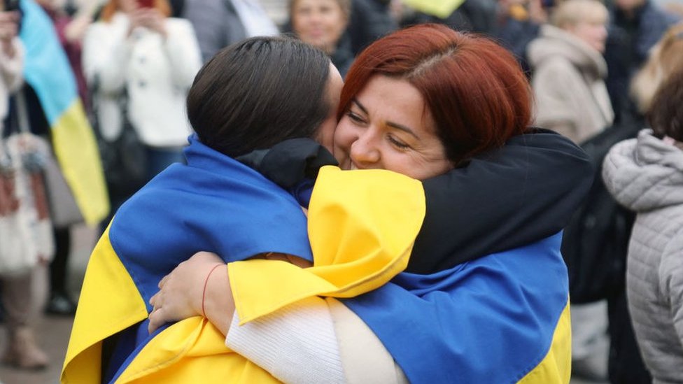 Dos mujeres con las banderas de Ucrania se abrazan en Odesa.