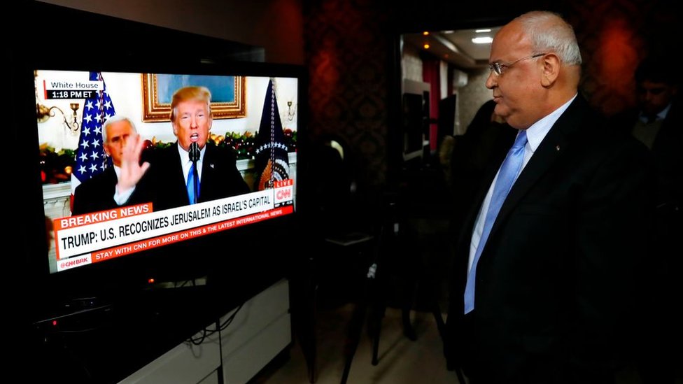 Saeb Erekat staring at Donald Trump on a screen