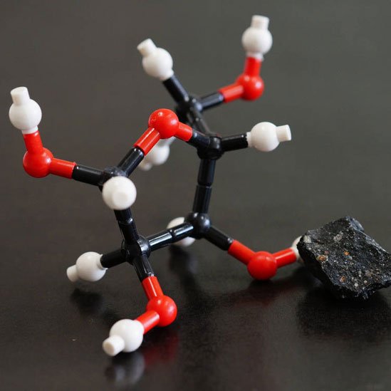 Estructura molecular de la ribosa junto a un trozo del meteorito Murchison