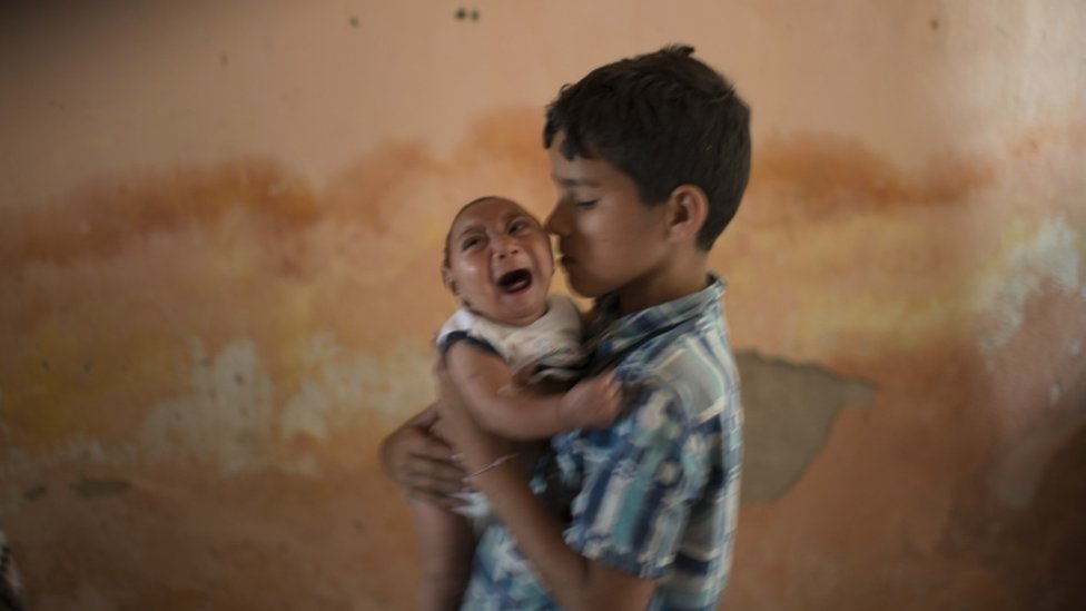 На этой фотографии от 23 декабря 2015 года 10-летний Элисон ухаживает за своим двухмесячным братом Хосе Уэсли в их доме в Поко-Фундо, штат Пернамбуку, Бразилия, рожденный с микроэнцефалией