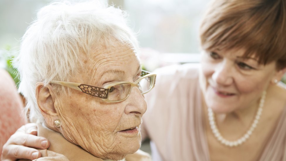 Una mujer anciana con demencia, acompañada por una mujer más joven