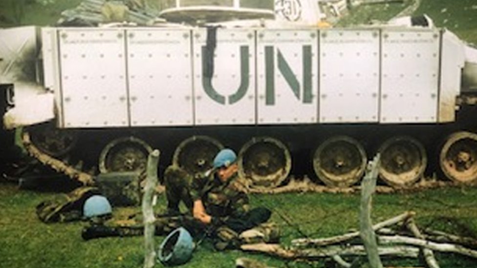 Shaun Pinner tendido frente a un tanque identificado con las iniciales UN