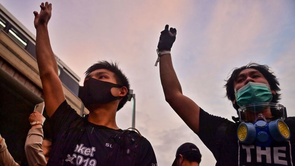 Pro-democracy protesters give the three-finger salute outside the Victory Monument BTS skytrain station in Bangkok on October 20, 2020