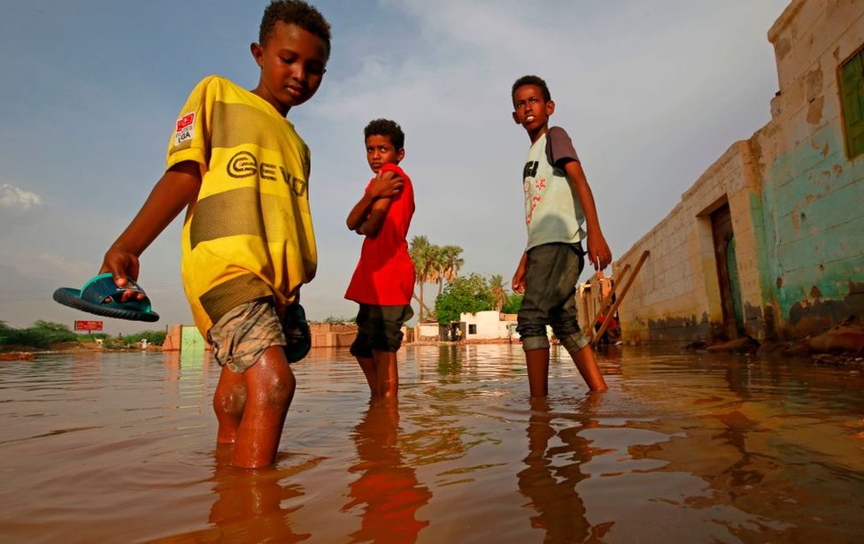 Sudanese boys make their way through a flooded street at alqamayir area in the capital's twin city of Omdurman, on August 26, 2020.