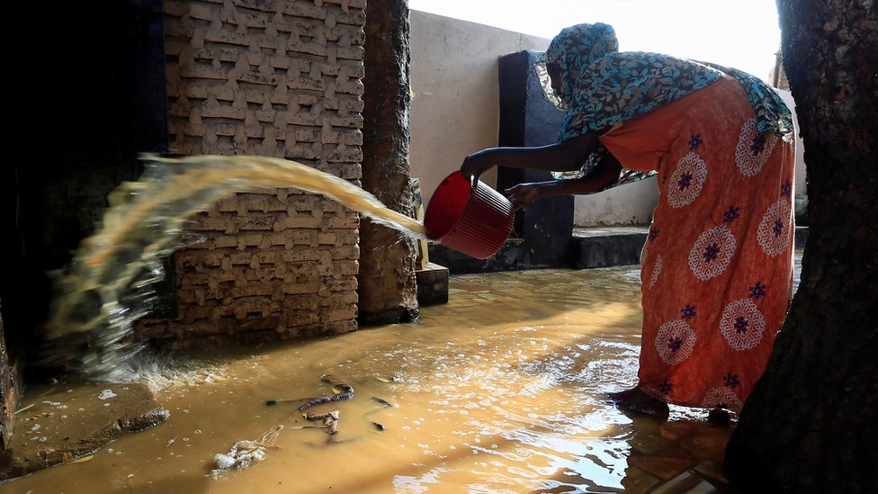 A resident pours out the waters of the Blue Nile floods from her backyard within the Al-Ikmayr area of Omdurman in Khartoum