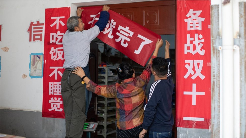 Employees post up slogans for the upcoming Double 11 online shopping festival at Lu Hong's photo albums factory on October 23, 2020 in Suzhou, Jiangsu Province of China.