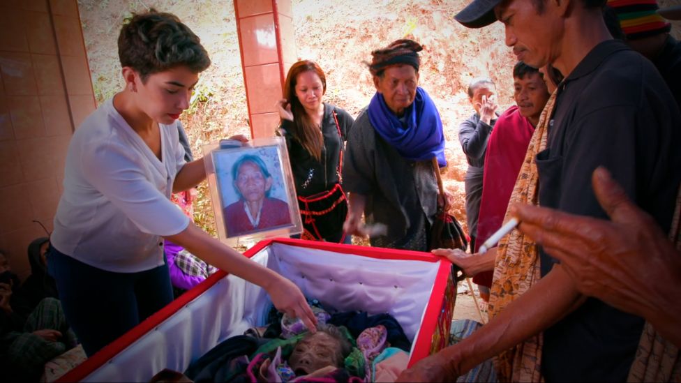 La periodista de la BBC Sahar Zand (izq.) visitó familias que mantienen a sus muertos en sus hogares durante muchos años. Esto les ayuda, aseguran, a mantener una conexión con sus seres queridos. Sahar Zand en un hogar junto a un féretro