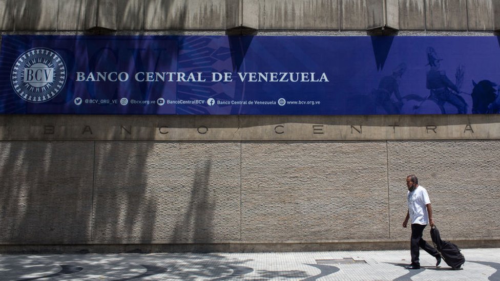 Un hombre camina frente a la fachada del Banco Central de Venezuela