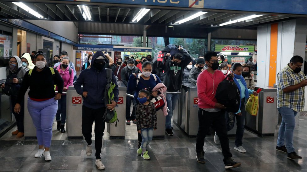 Люди в защитных масках проходят мимо турникетов на станции метро в Мехико