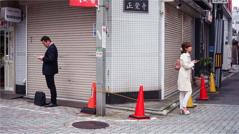 Dos personas en la calle con sus teléfonos.