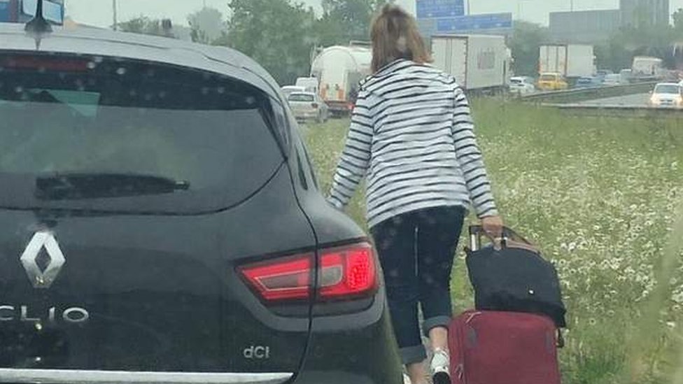 женщина идет по дороге с багажом