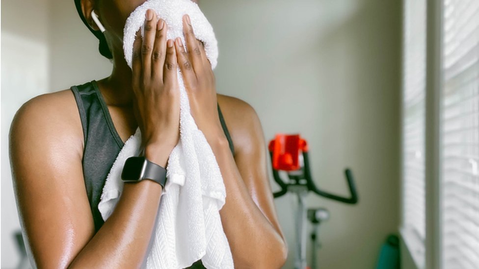 Una mujer se seca el sudor con una toalla luego de hacer ejercicio.