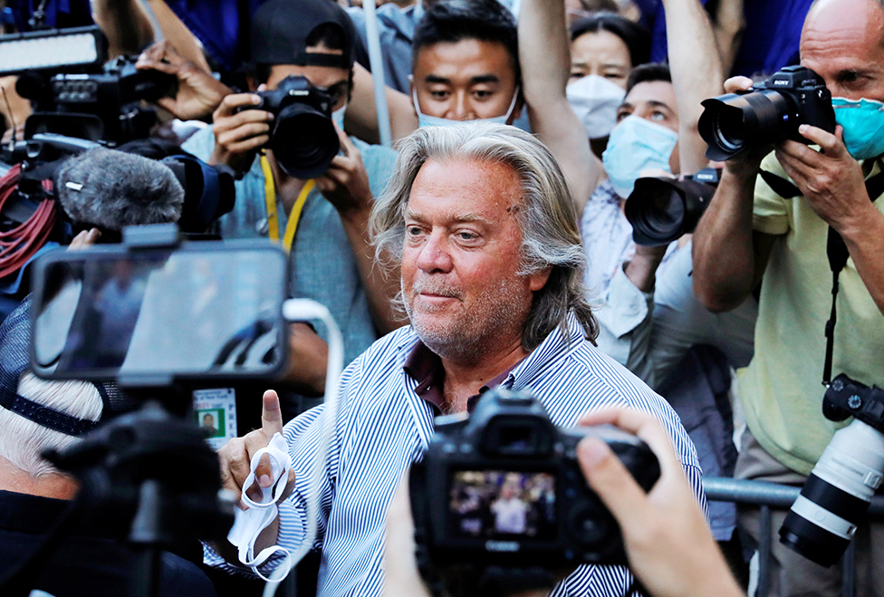 Steve Bannon stands outside court surrounded by photographers