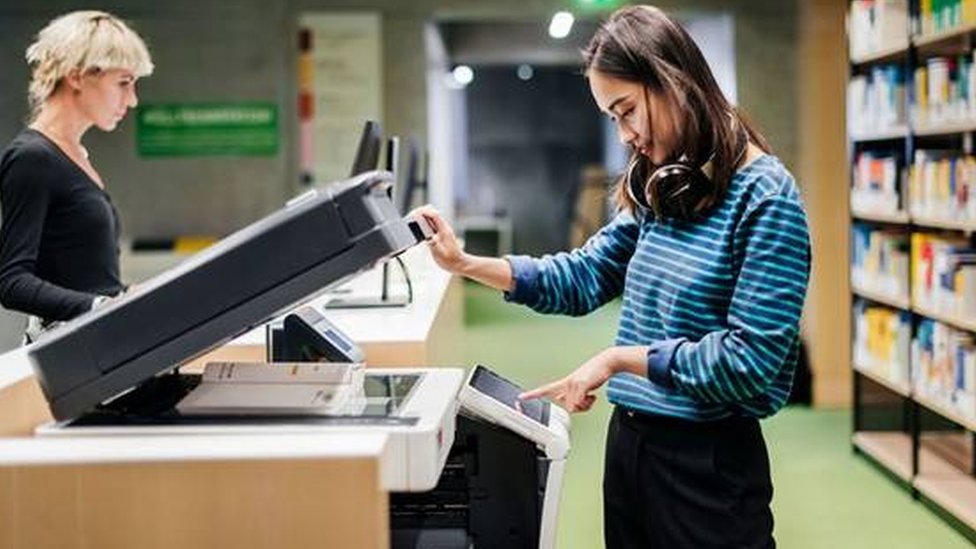 Colegas de trabalho ao lado de uma fotocopiadora