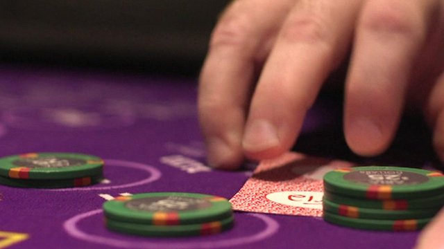 A hang hovers over casino chips and a playing card