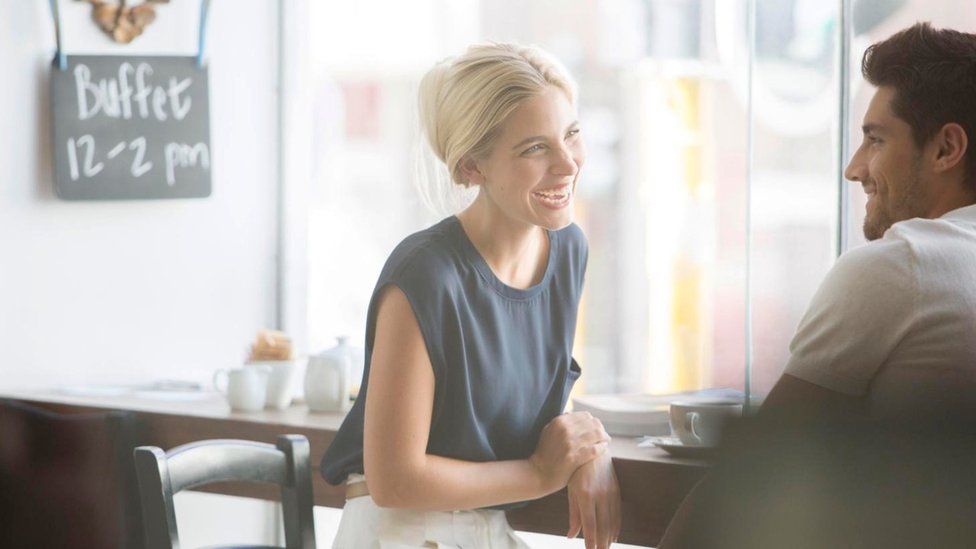 Tener mala ortografía puede incluso afectar tus oportunidades de encontrar pareja, si utilizas sitios online. Una pareja charlando y ríendo en un café