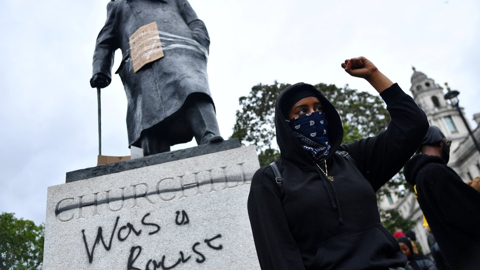 Pengunjuk rasa berdiri di depan patung Churchill.