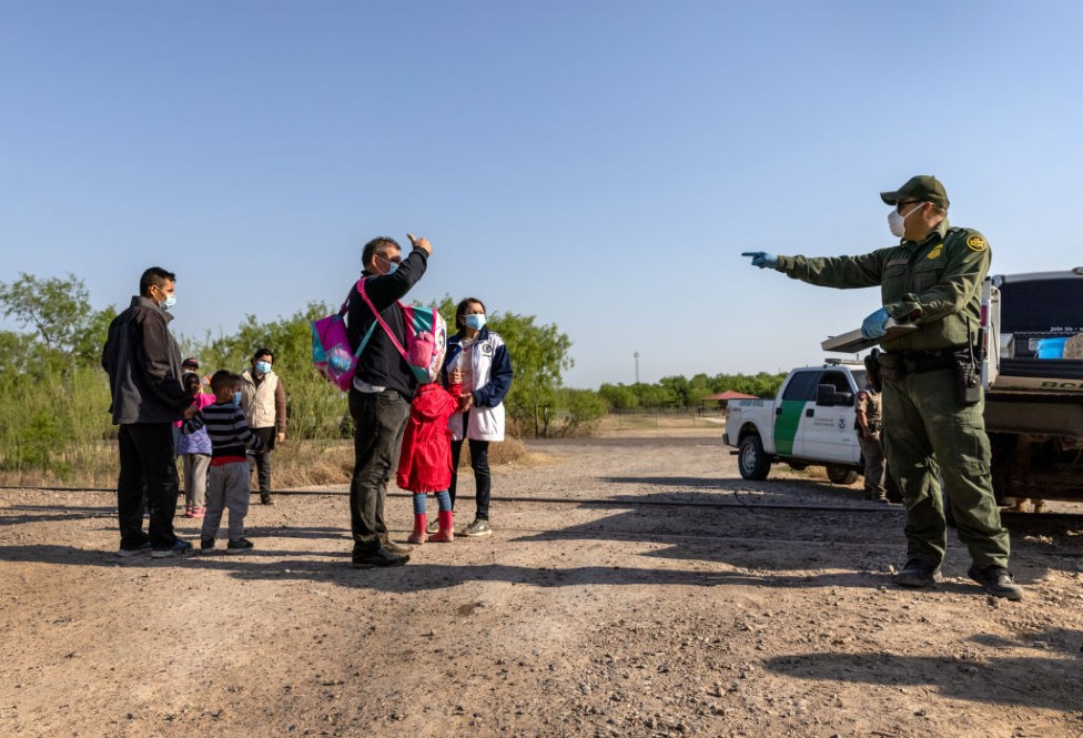 Un agente de la patrulla fronteriza de EE.UU. conversa con una familia venezolana que cruzó la frontera desde México. La foto se tomó el 26 de marzo en Peñitas, Texas.