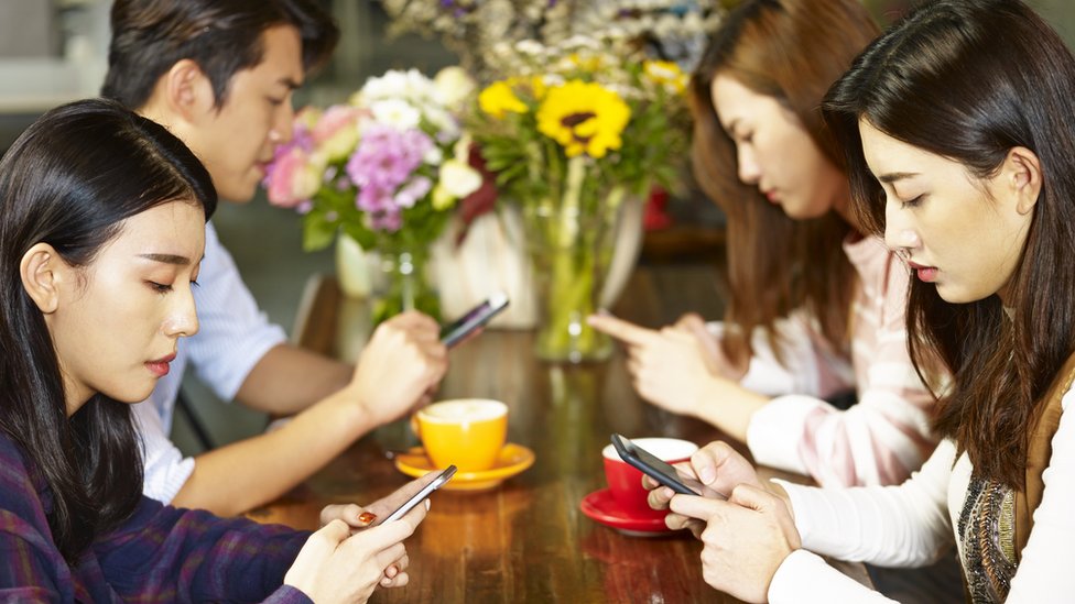 Jóvenes asiáticos mirando sus teléfonos celulares