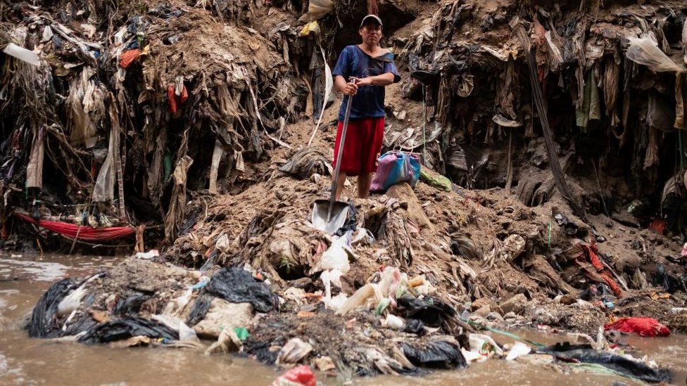Un hombre con una pala que trabaja informalemente en el contaminado río Las Vacas