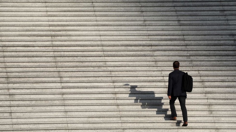 Aceptar el desafío de pensar en ideas contradictorias puede ayudarte a subir la cuesta del liderazgo. hombre sube escalera