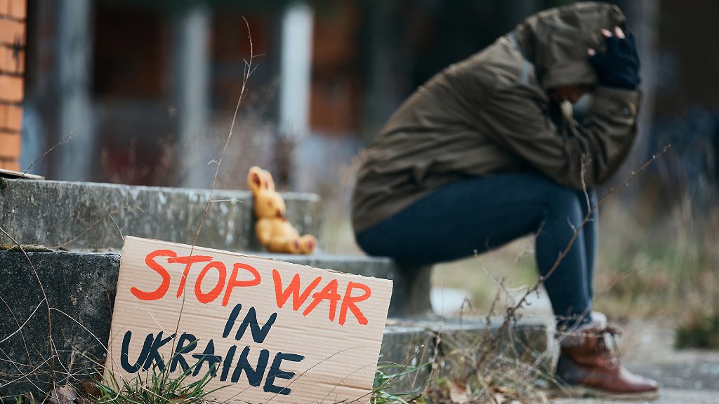 Mujer desesperada con cartel que dice: "Paren la guerra en Ucrania".