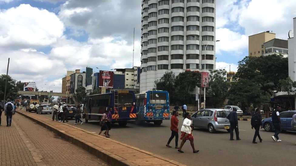 Пешеходы переходят шестиполосную дорогу University Way в Найроби, не обращая внимания на пешеходный мост (на заднем плане)