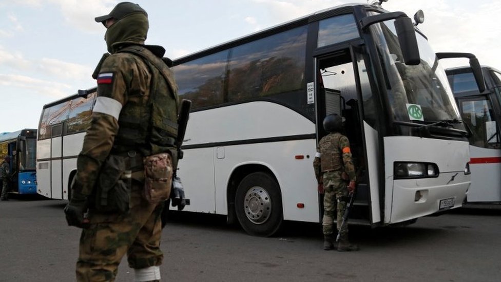 صورة يُزعم أنها تُظهر قوات موالية لروسيا تقف في قرية أولينيفكا بجوار حافلات تقل مقاتلين أوكرانيين من ماريوبول