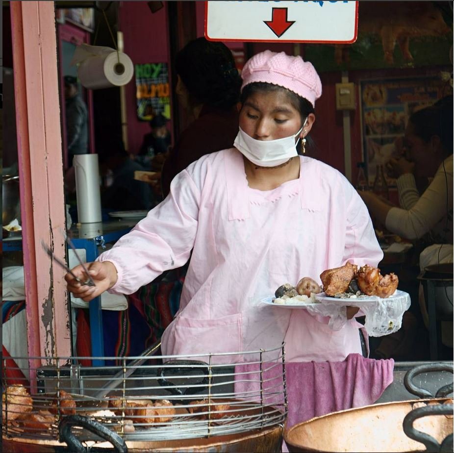 Mujer con tapabocas saca un chicharrón de una fritadora Mujer con tapabocas saca un chicharrón de una fritadora