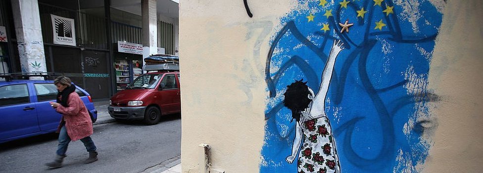 Женщина проходит мимо граффити с изображением молодой девушки, пытающейся достичь звезд с флага ЕС 18 февраля 2012 года в Афинах, Греция