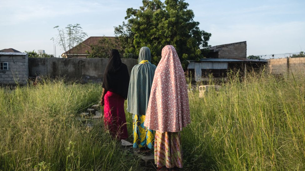 Tres niñas caminan de casa en Maiduguri, Nigeria, a un campamento para personas desplazadas, 2019